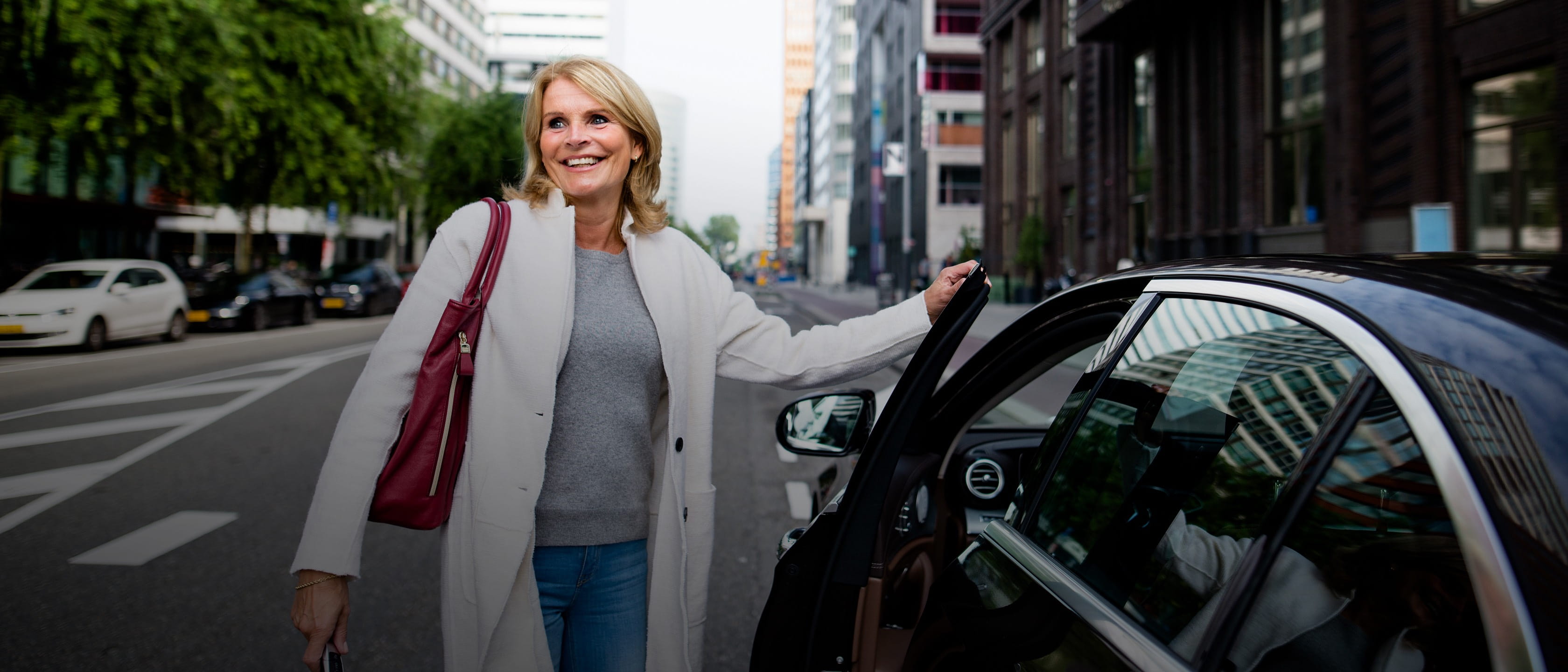 Happy woman on city street getting into car